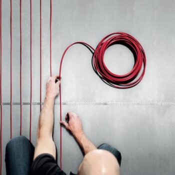 master ukladivaet tonkiy kabel мастер укладывает на пол тонкий кабель для теплого пола